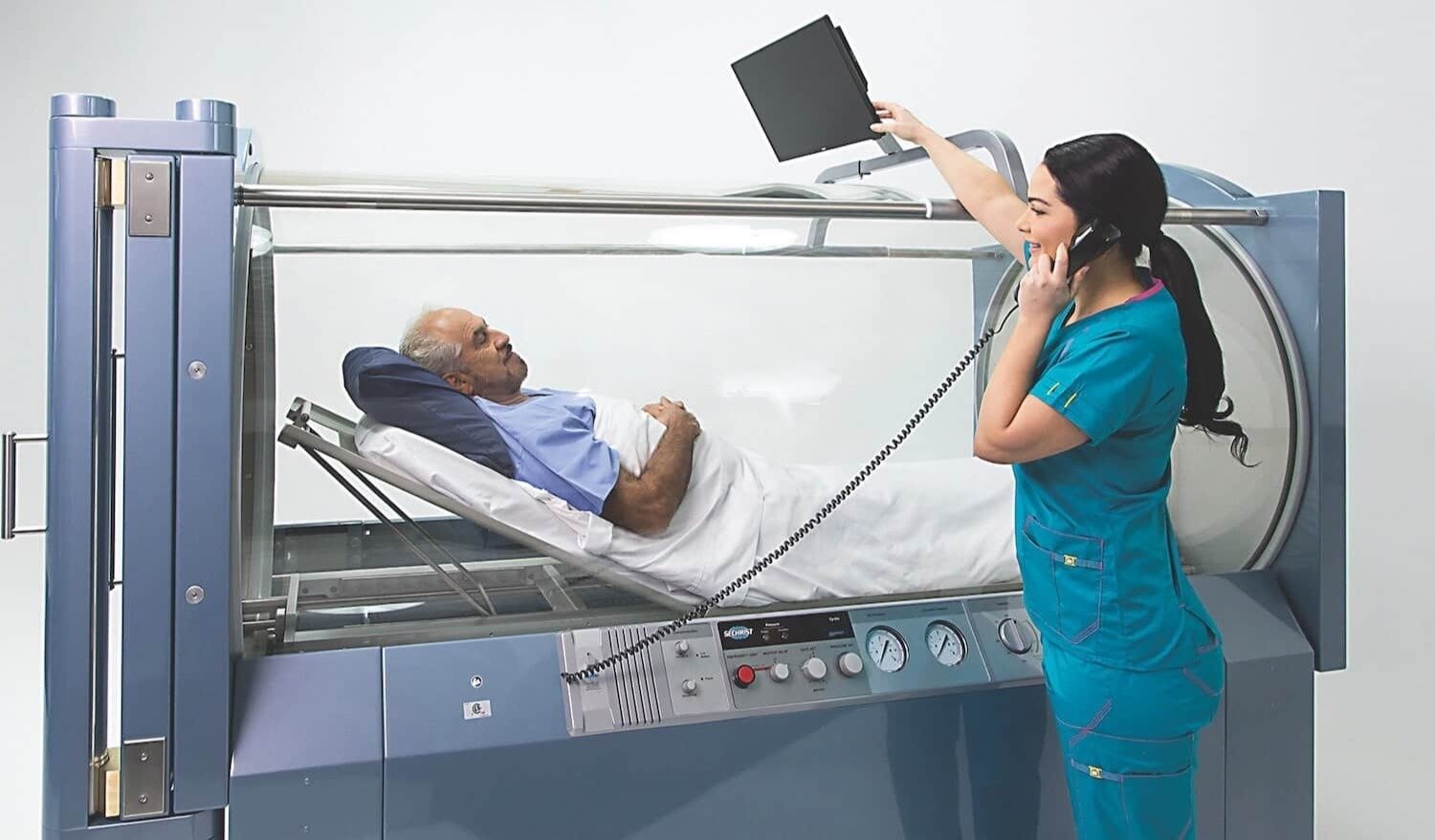 A Pacific Hyperbarics clinician monitoring a patient during a hyperbaric oxygen therapy session in a Sechrist chamber