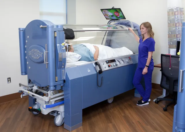 Nurse assisting a patient into the chamber